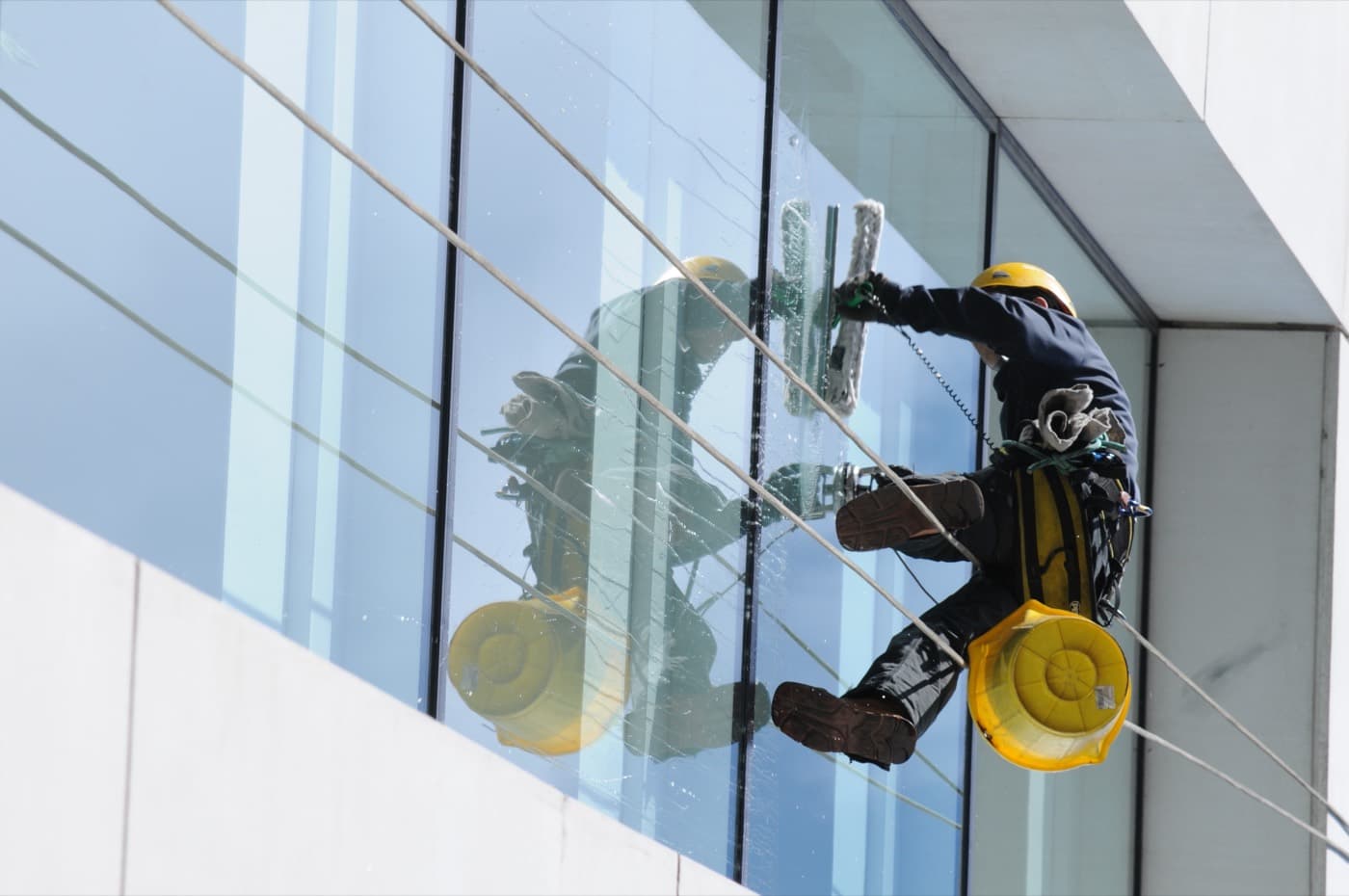 Professional high-rise window cleaner working on exterior glass