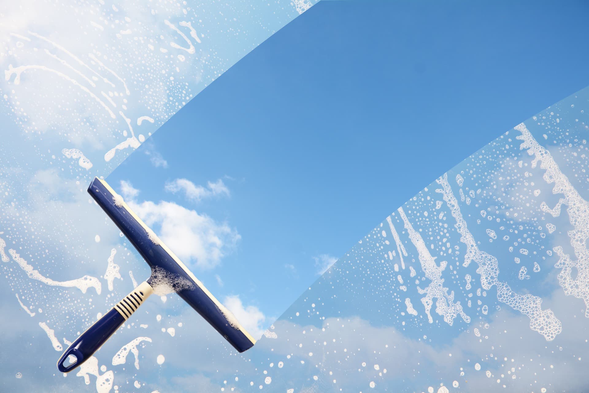 Professional window cleaning squeegee revealing a clear blue sky